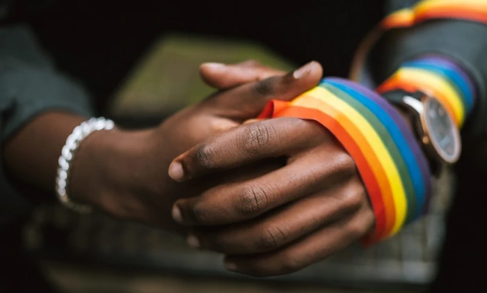 Black hands with rainbow ribbon